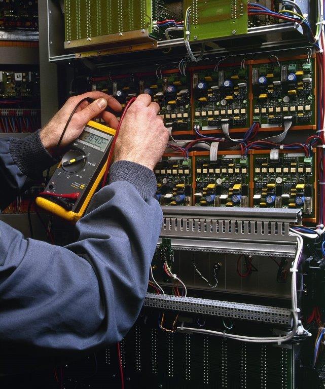 Industrial maintenance technician troubleshooting inside a control cabinet