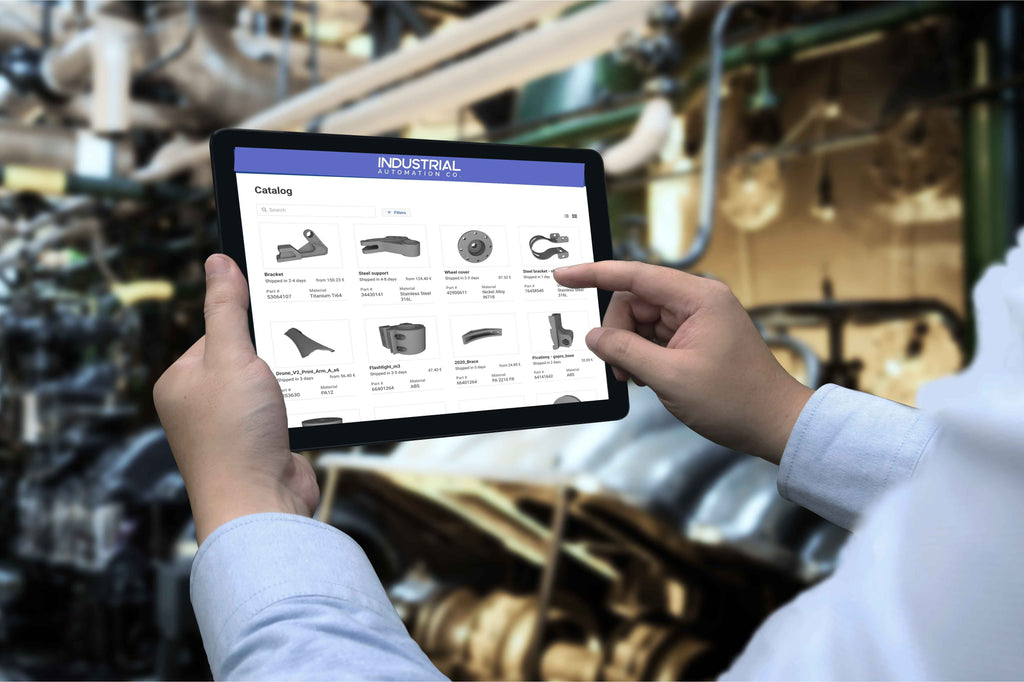 Engineer using Industrial Automation Co. digital spare parts catalog on a tablet in a factory.
